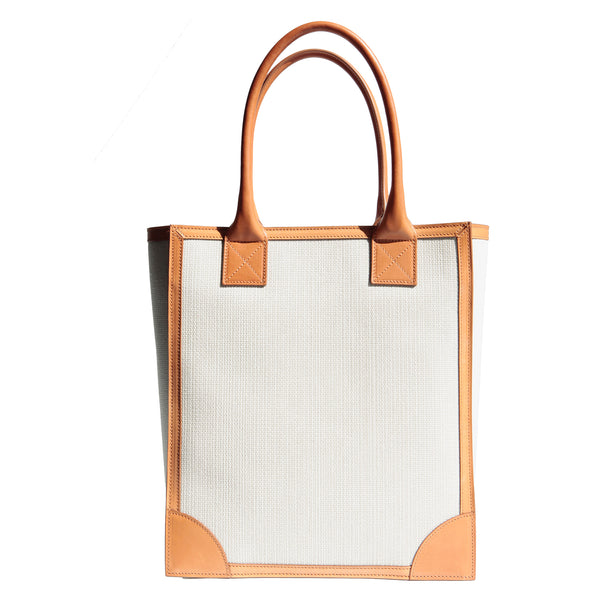 Vertical shopper tote in canvas body with natural veg-tan leather trim around the borders and the long handles. Wear comfortably over the shoulder or carry by the handles. Spacious interior for work essestials. Structured body for the power casual wear.