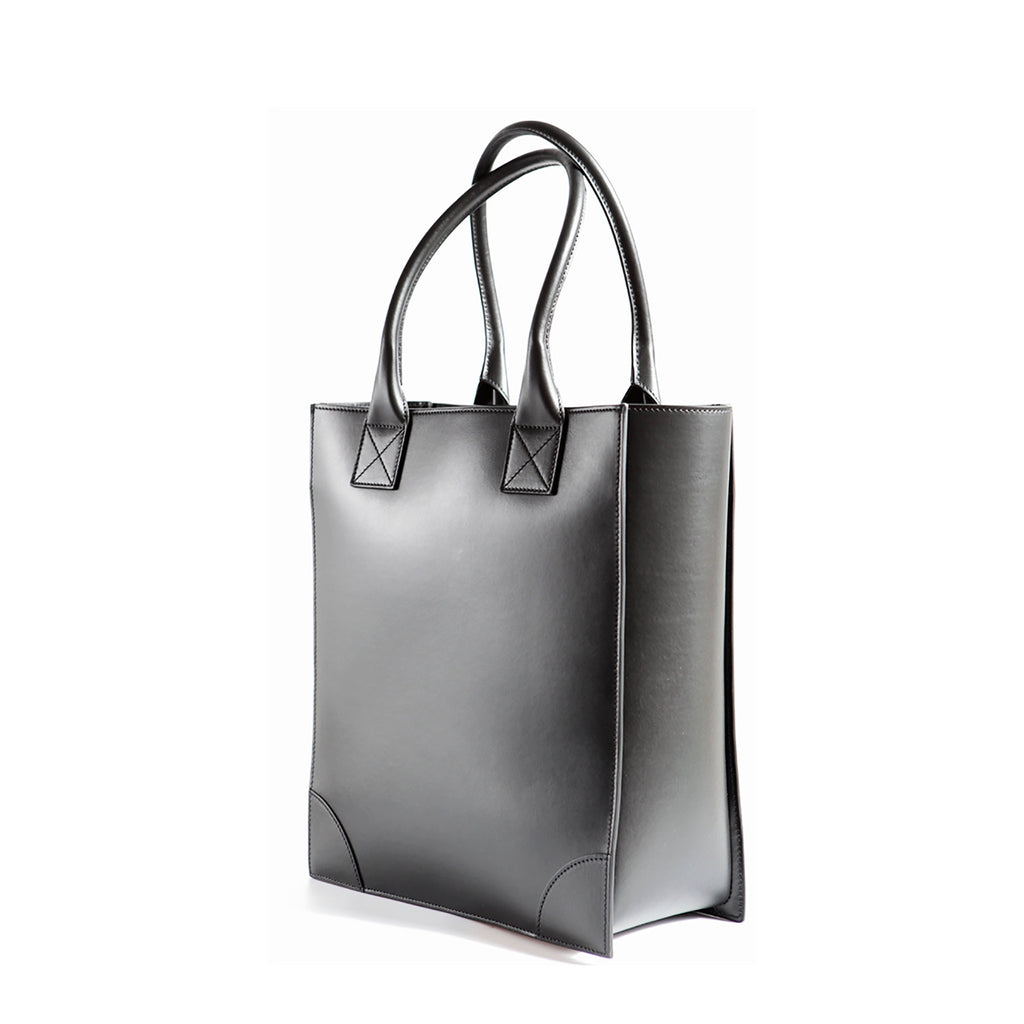 Side view of the black vertical leather tote bag with long handles to carry over the shoulder. Structured body with smooth Italian Leather.