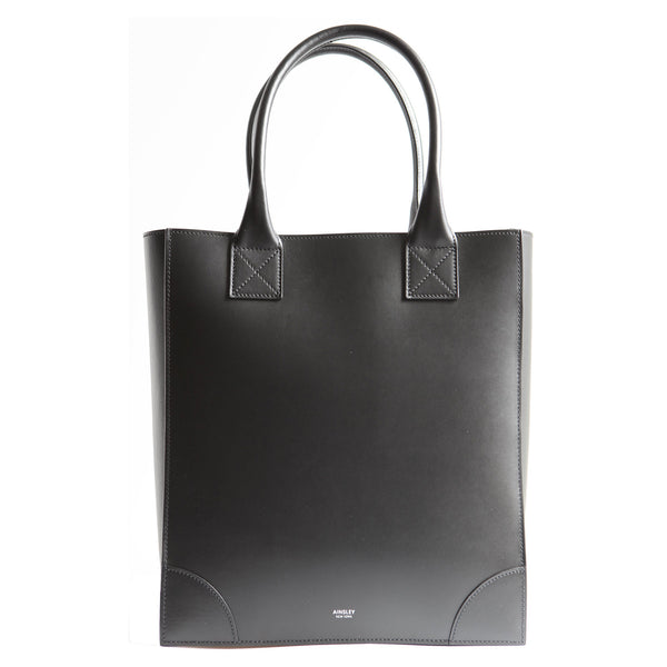 The Duke is a black vertical leather tote bag with long handles to carry over the shoulder. Structured body with smooth Italian Leather.